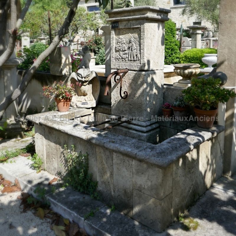 Fountain in natural stone with a pediment hand-sculpted with a rural scene