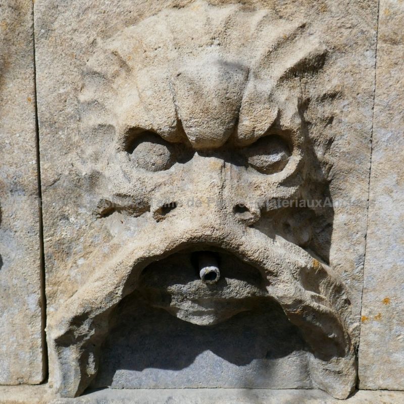 Détail de la tête de faune sculptée à la main sur notre fontaine murale en pierre de style Renaissance.